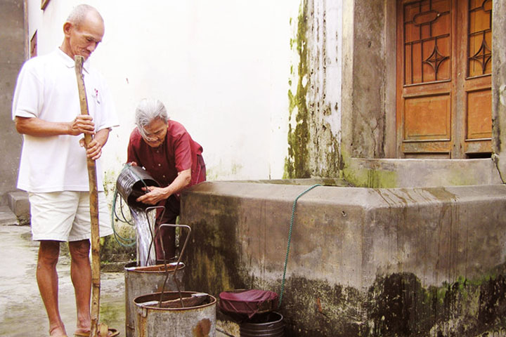 90-year-old carrying water man Hoi An